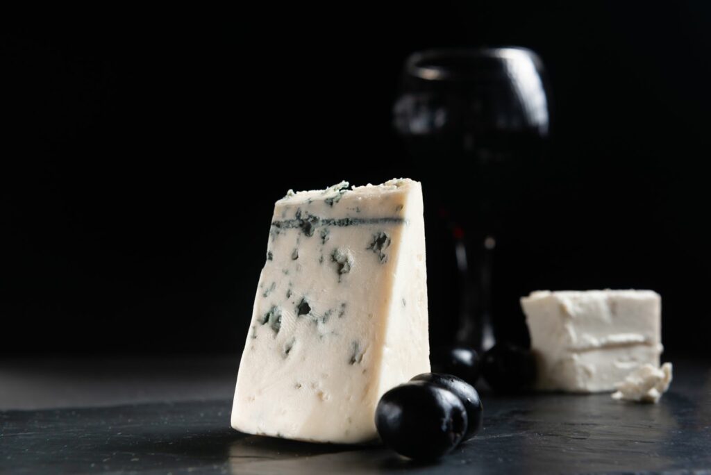 french roquefort cheese with olives on a dark background moldy cheese with olives blue cheese on black background